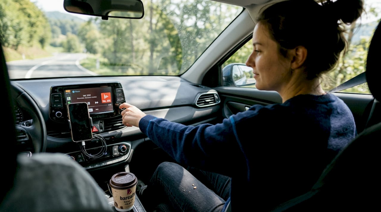 Med vožnjo si ženska prilagodi glasnost avtoradia.