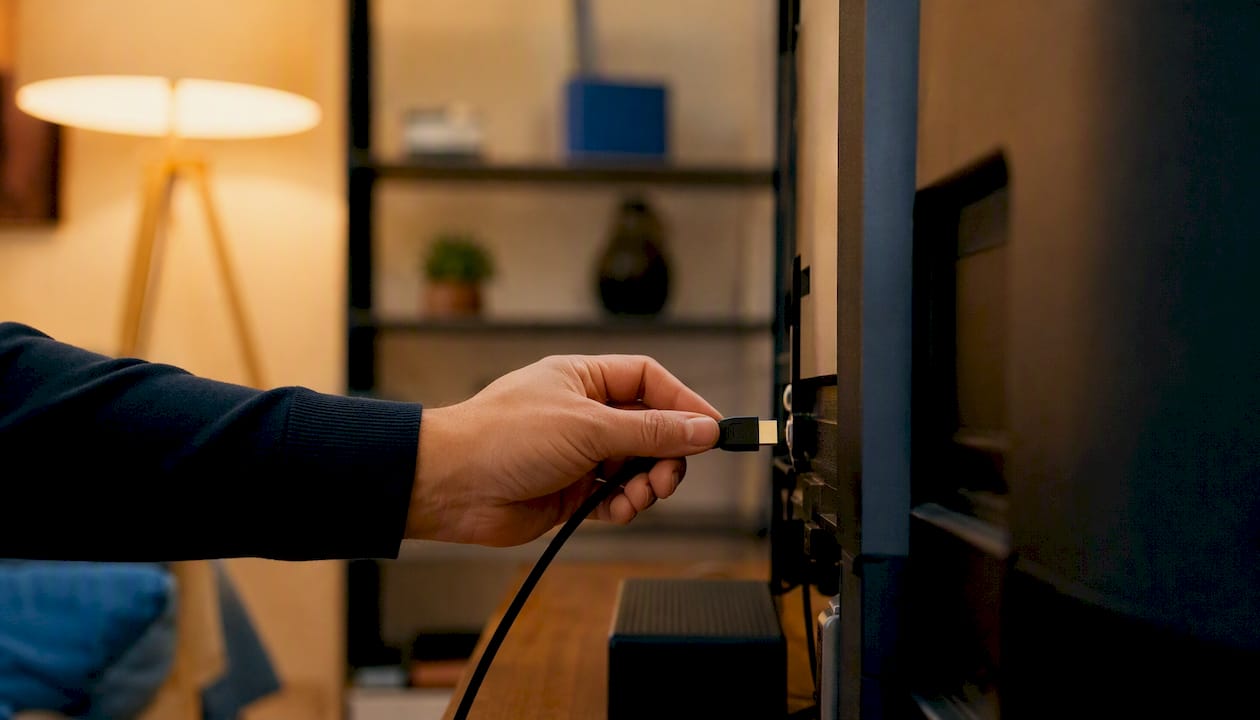 Roka priključuje HDMI kabel v vhod naprave.