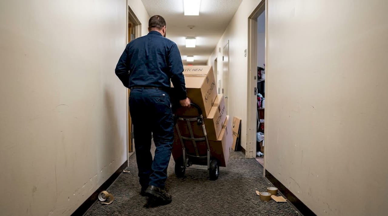 Mover handling boxes down apartment hallway