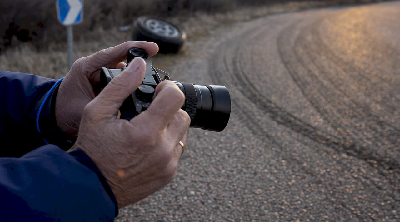 Close-up of hands photographing skid marks on road