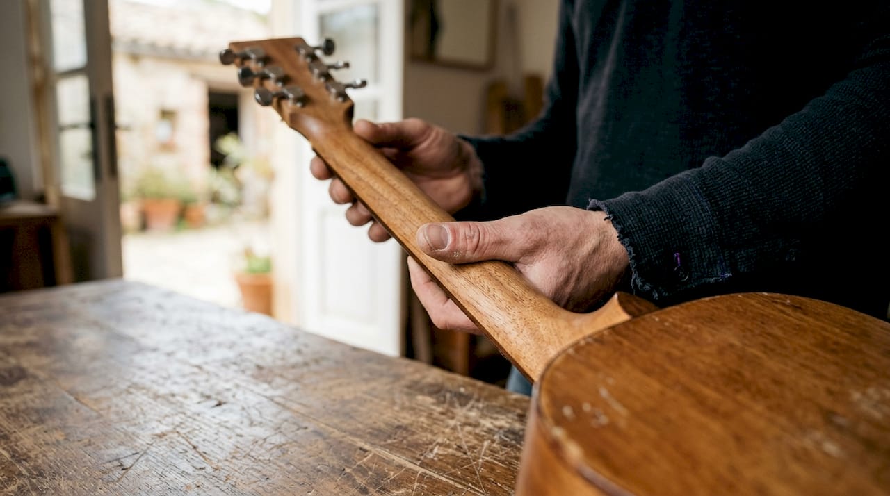 Hand holding handcrafted guitar neck detail