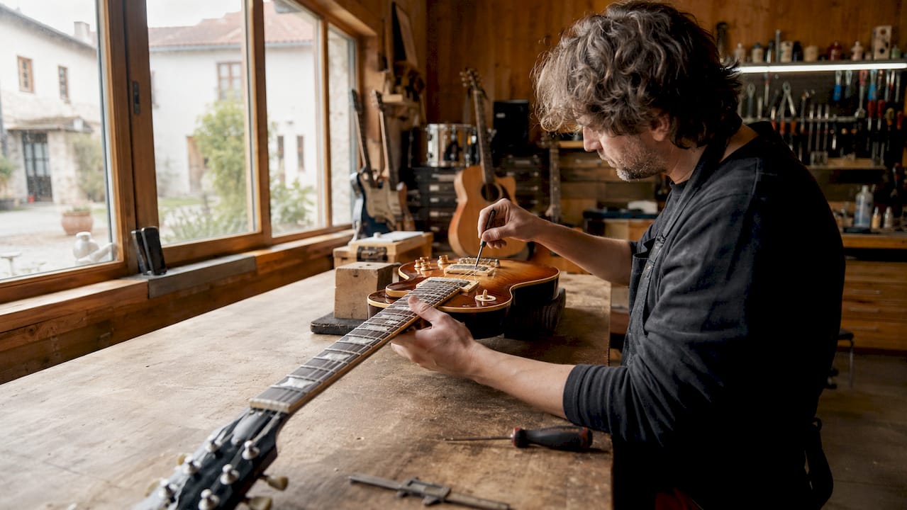 Mit geschickten Händen wird der Gitarrensteg präzise eingestellt.
