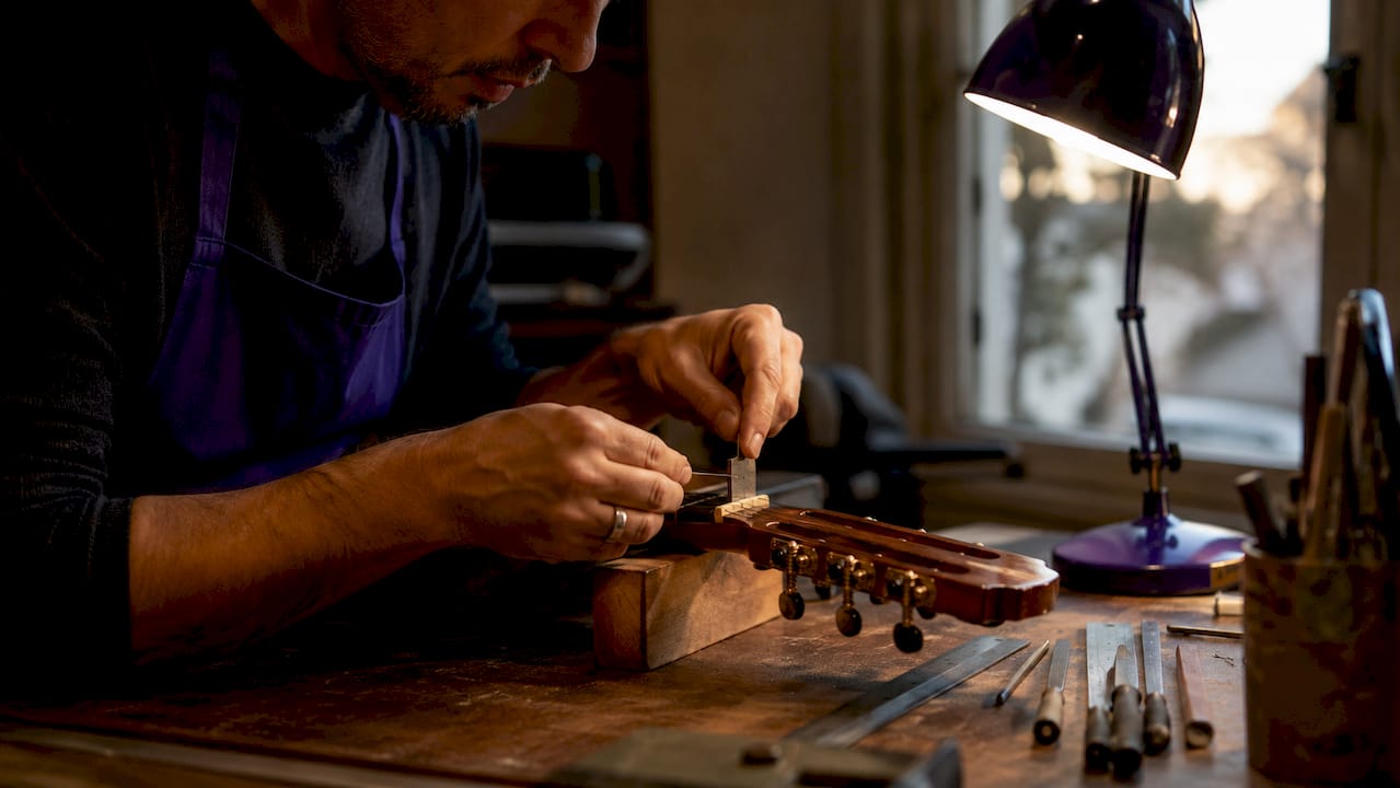 Hands measuring flamenco guitar nut slot height