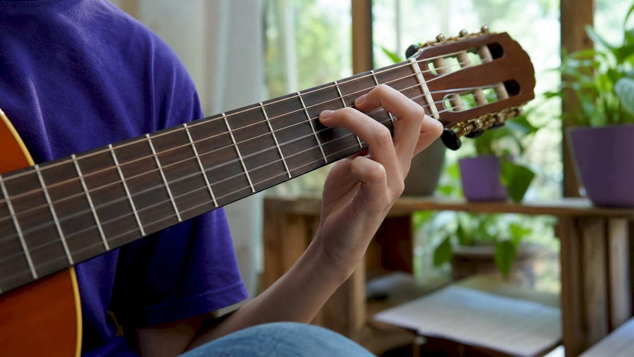 Close-up of hands pressing nylon strings on classical guitar