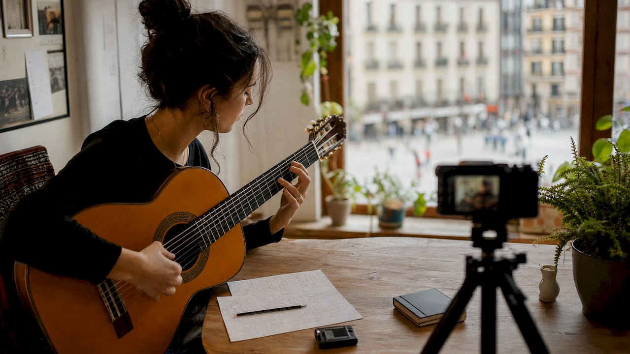 Eine Frau gibt Online-Unterricht in Flamenco-Gitarre und nutzt dafür eine Kamera.