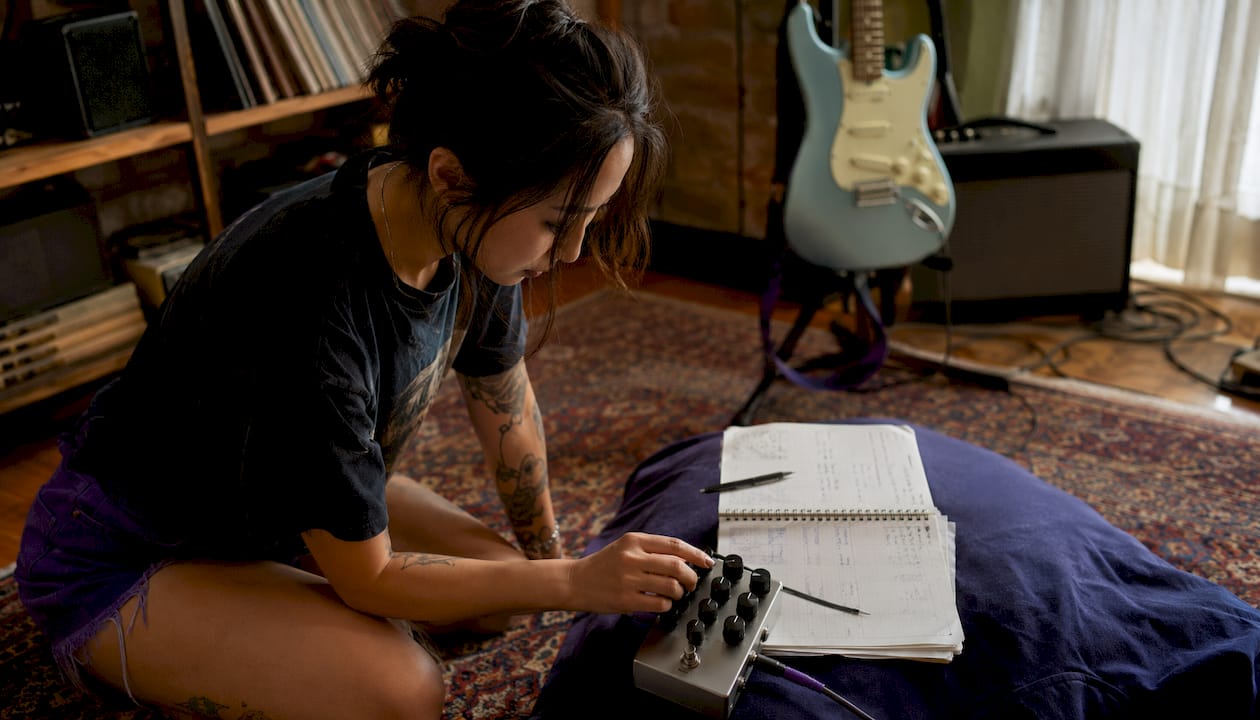Guitarist adjusting compressor pedal controls