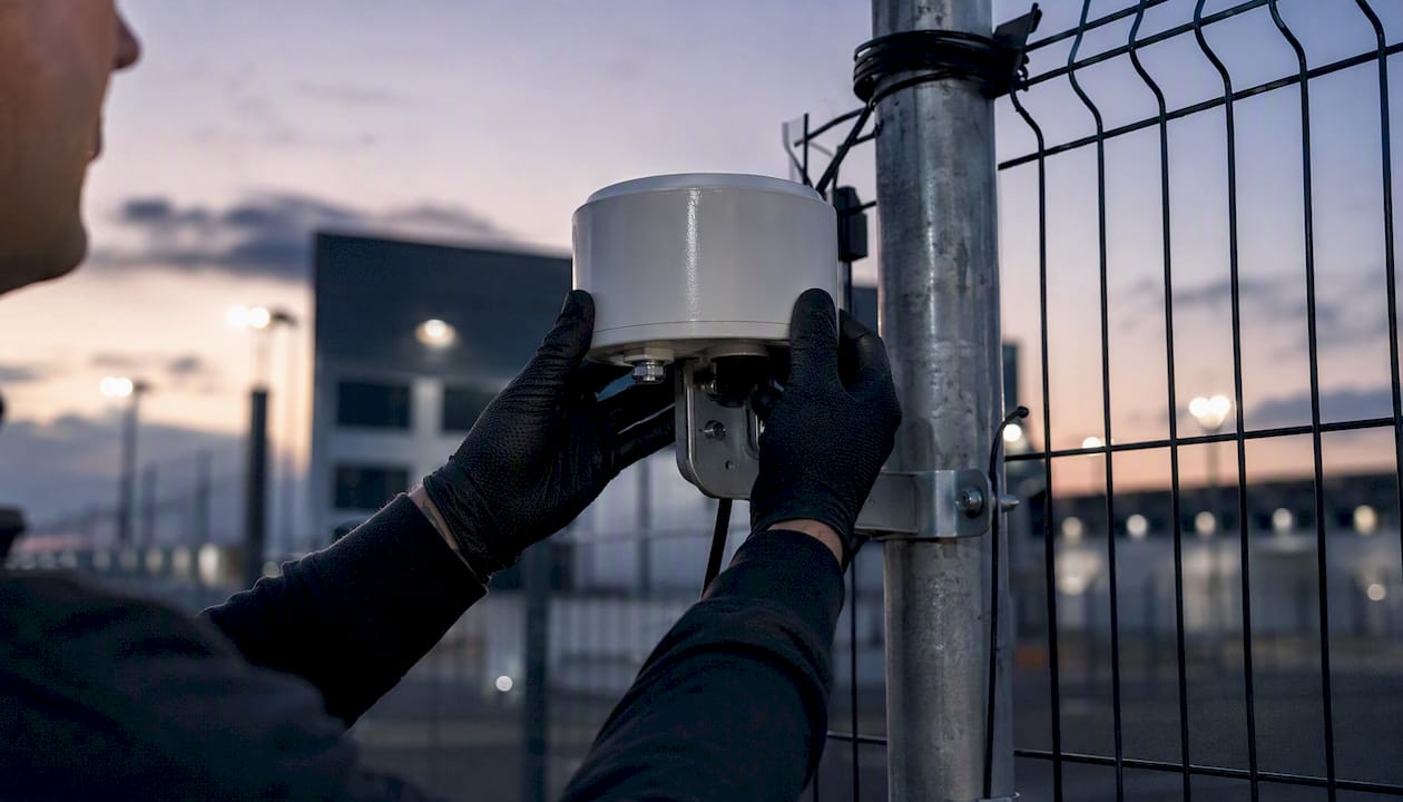Hands installing perimeter radar sensor outdoors