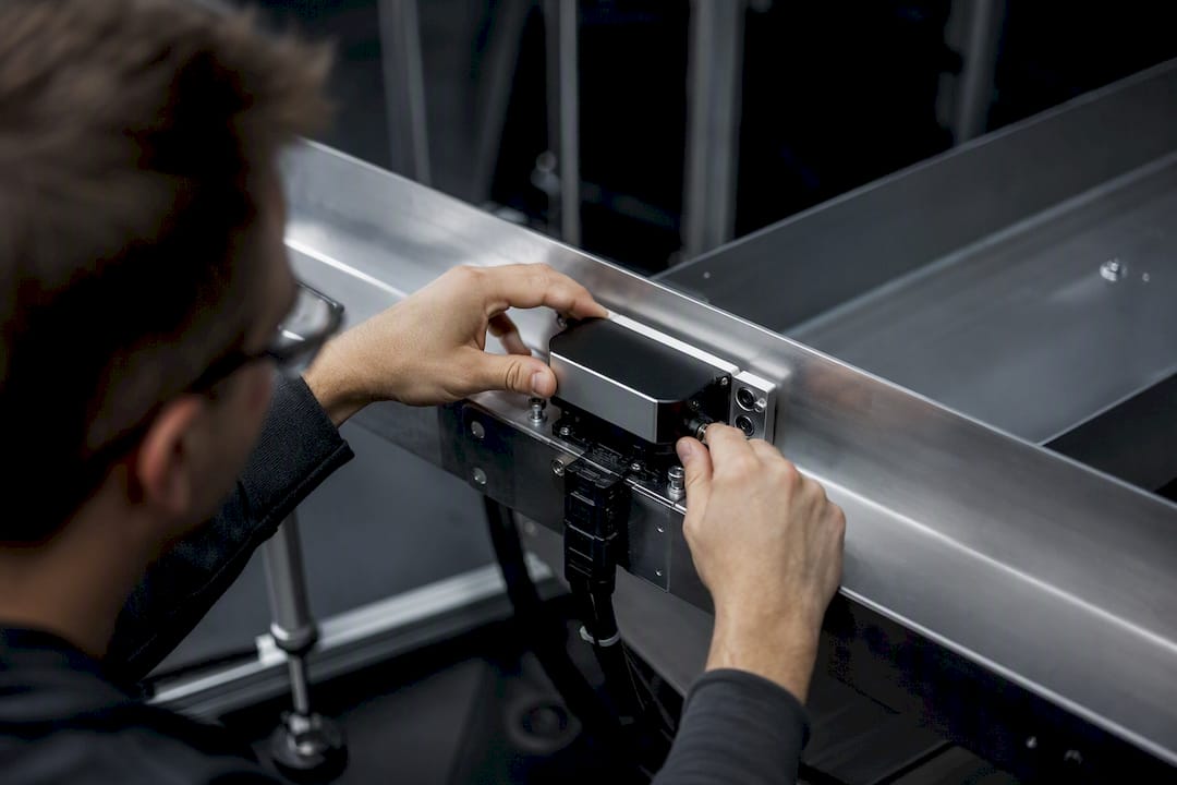 Hands installing sensor on industrial framework