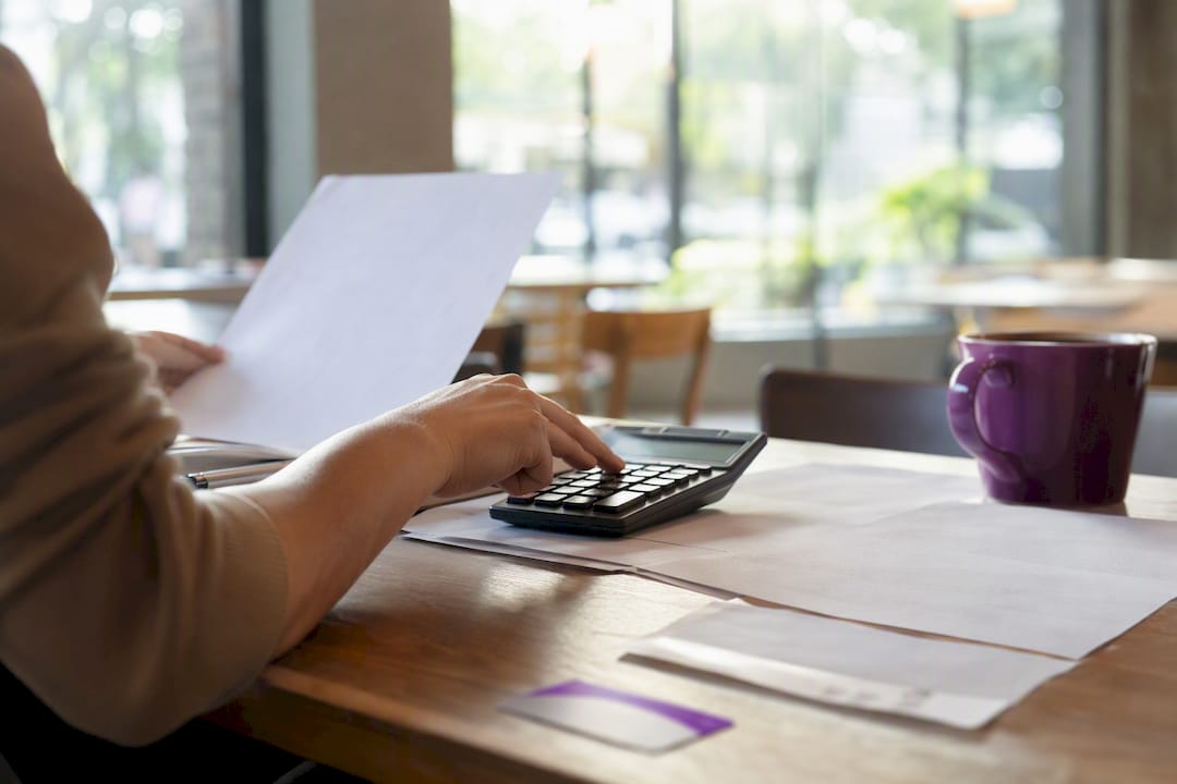 Hands using calculator with hospital bills and insurance card
