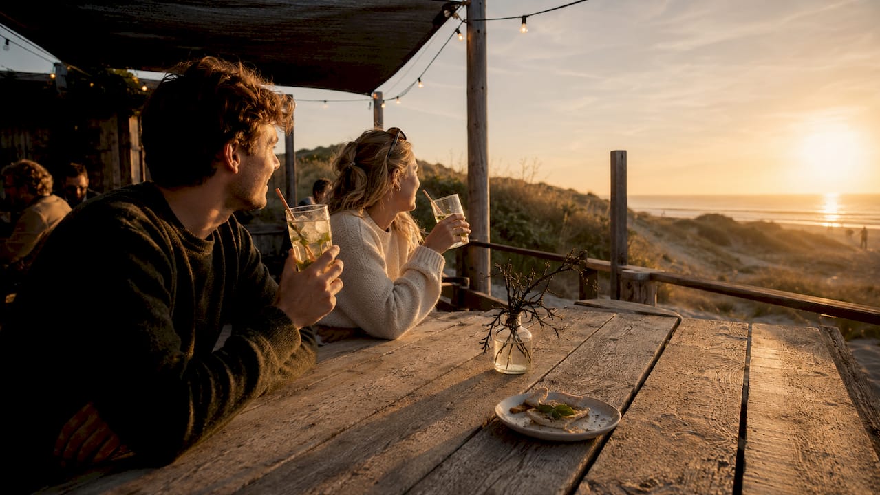 Stelletje geniet van een drankje op het terras van een strandpaviljoen op Ameland.