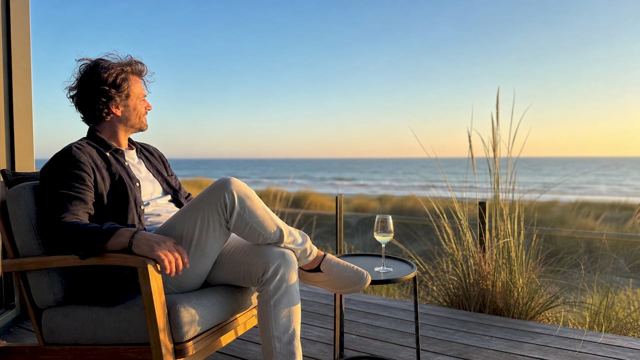 Vanaf het balkon van zijn luxe appartement geniet een man van het prachtige uitzicht.