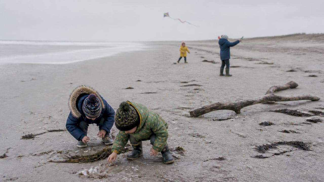 Kinderen die spelen op het winterstrand van Ameland
