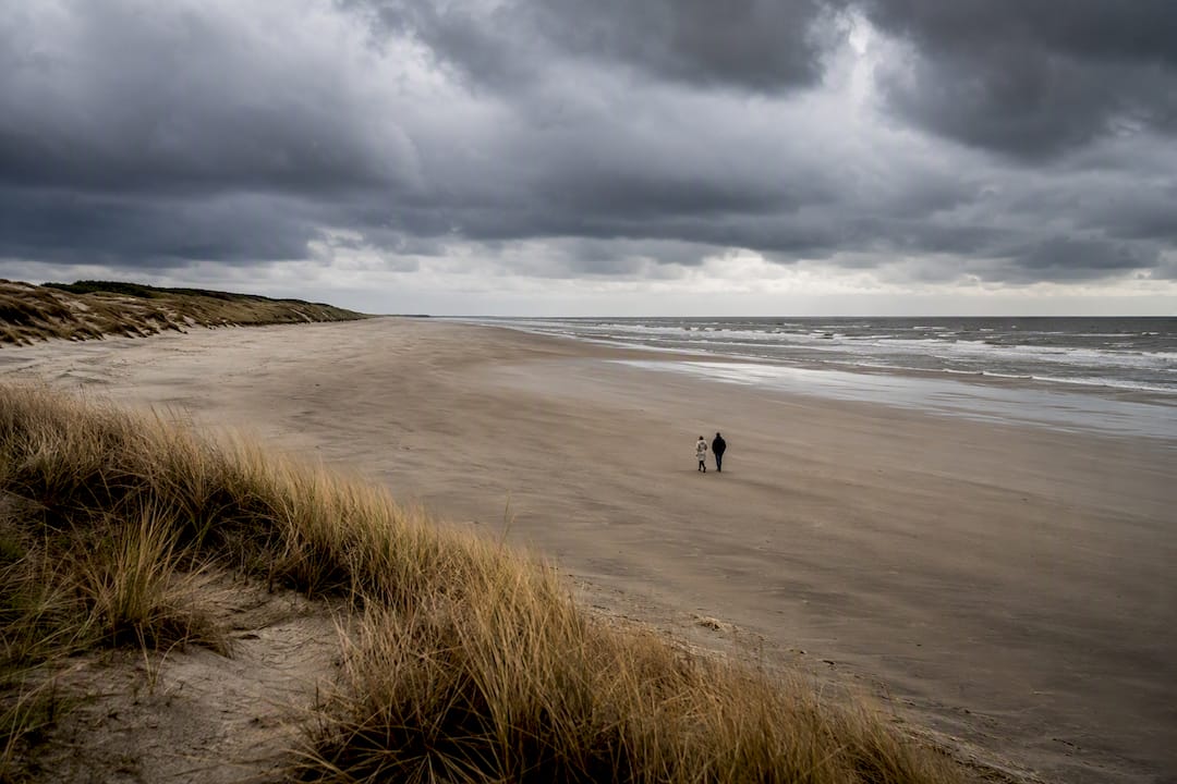 Stel wandelt over een verlaten strand in de herfst