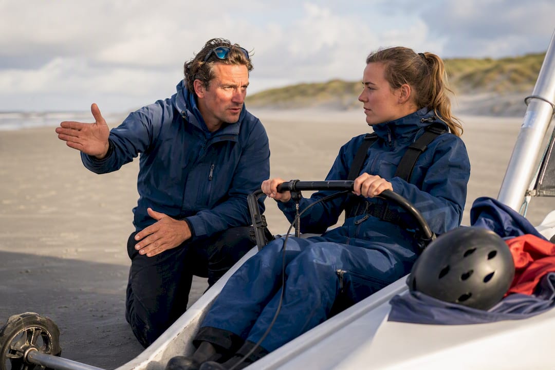Begeleider geeft instructies aan beginnende strandzeiler