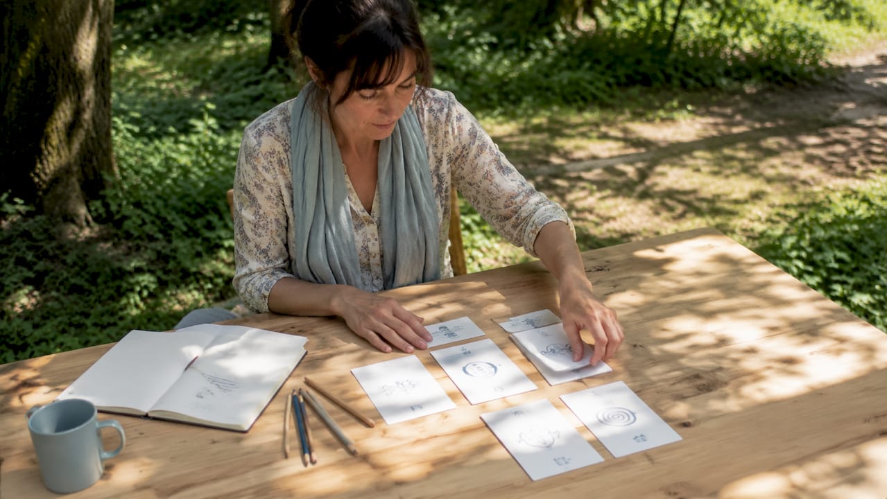 Des mains disposent soigneusement des cartes d’exercices pour l’échauffement de la voix sur une table.