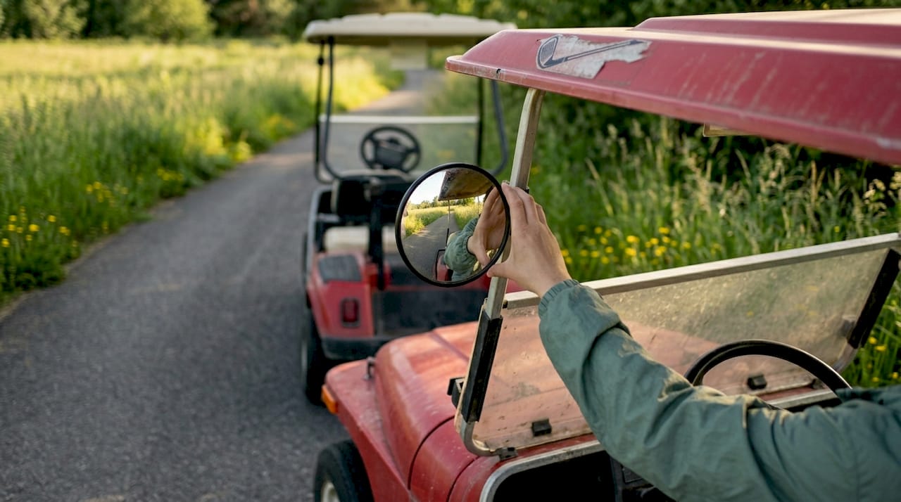 Woman adjusting convex side mirror on golf cart