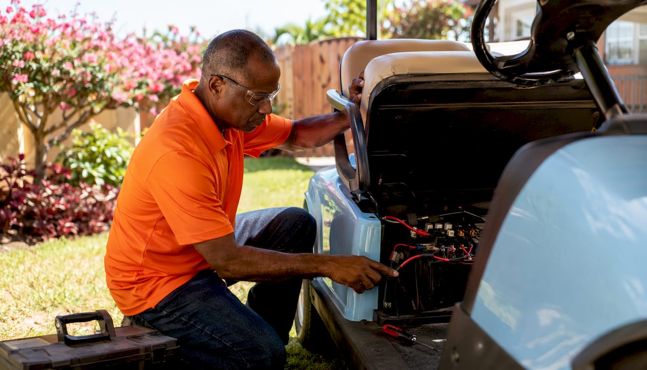 Man inspecting golf cart fuse block outdoors