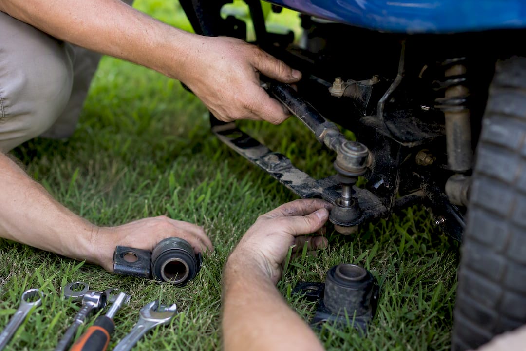 Hands inspecting golf cart steering and suspension parts