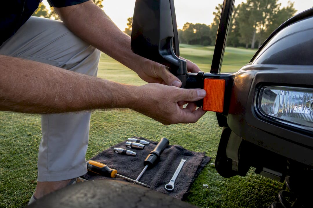 Hands checking golf cart parts for inspection readiness