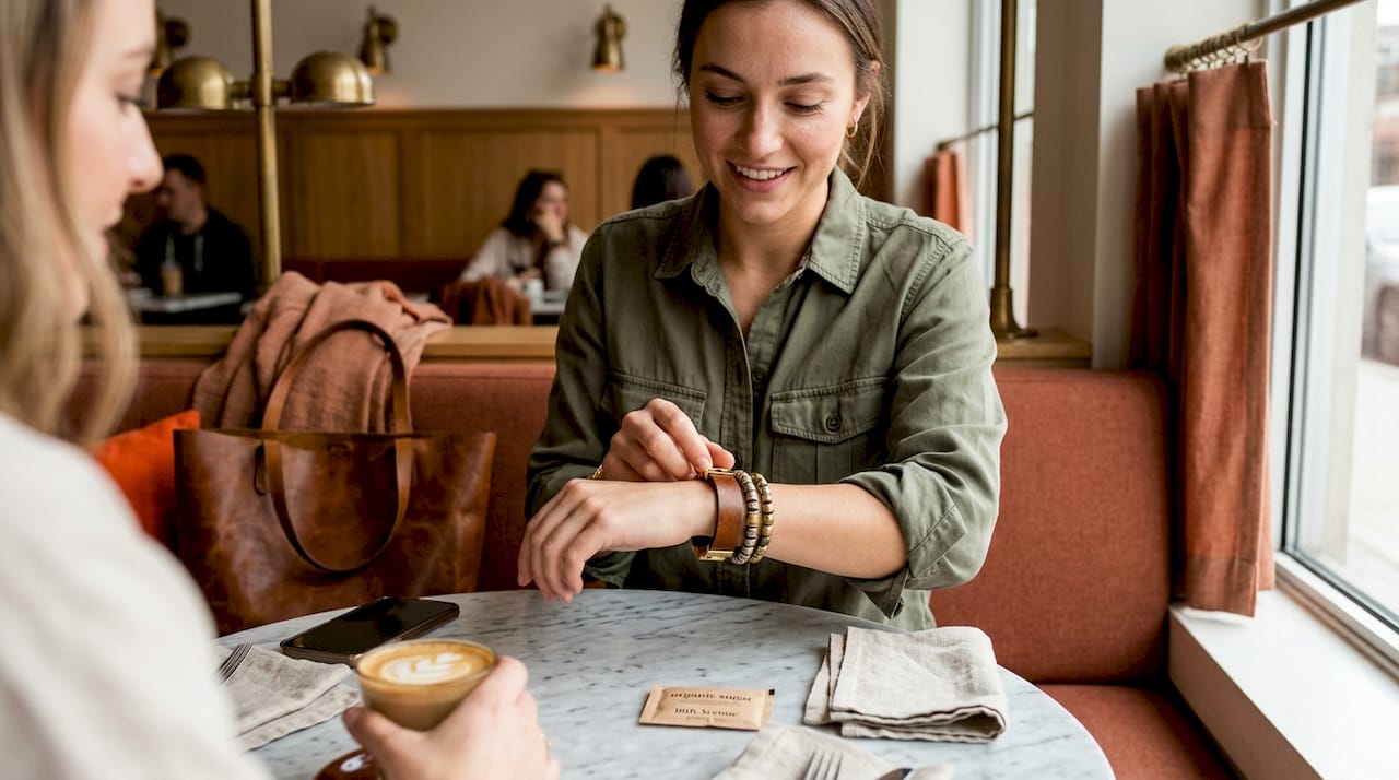Woman wearing mixed metal bracelets at café table