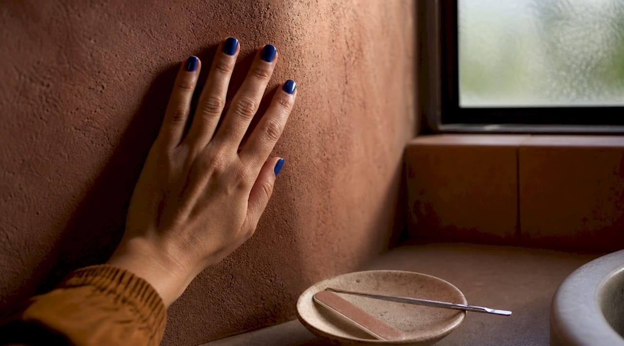 Hands with cobalt blue satin finish nails and manicure tools