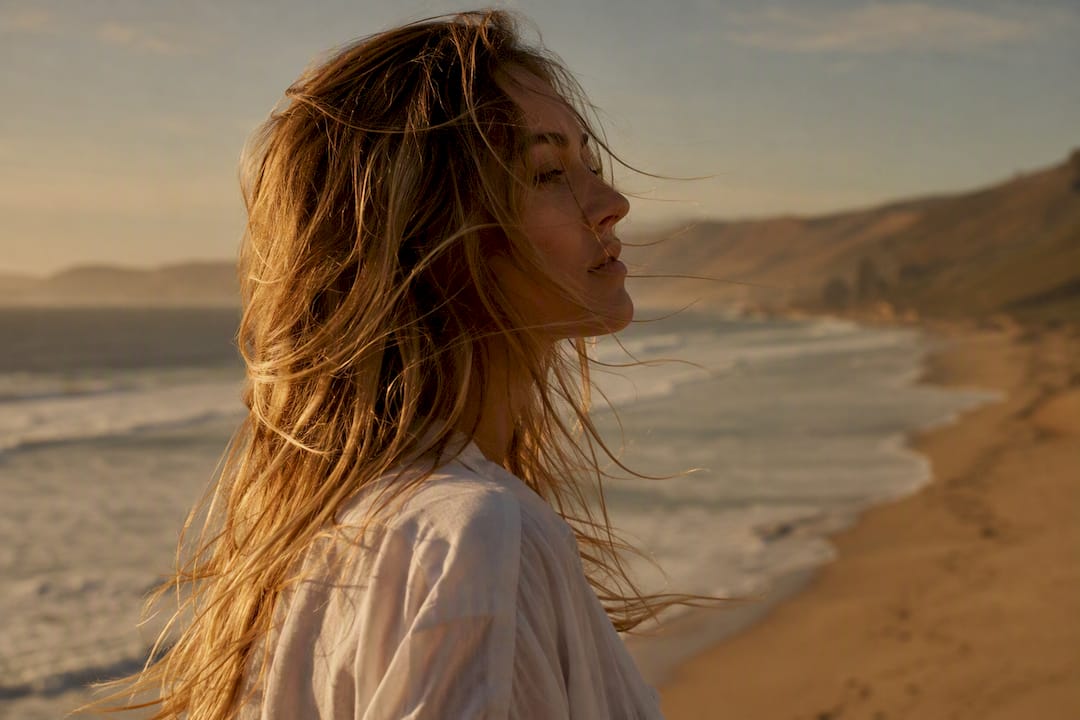 Woman with loose beach waves by coast