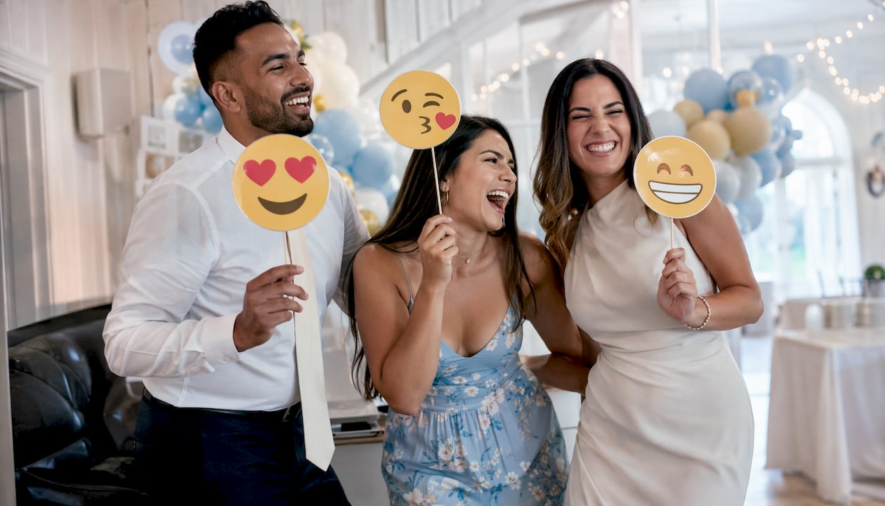 Guests laughing with emoji party props