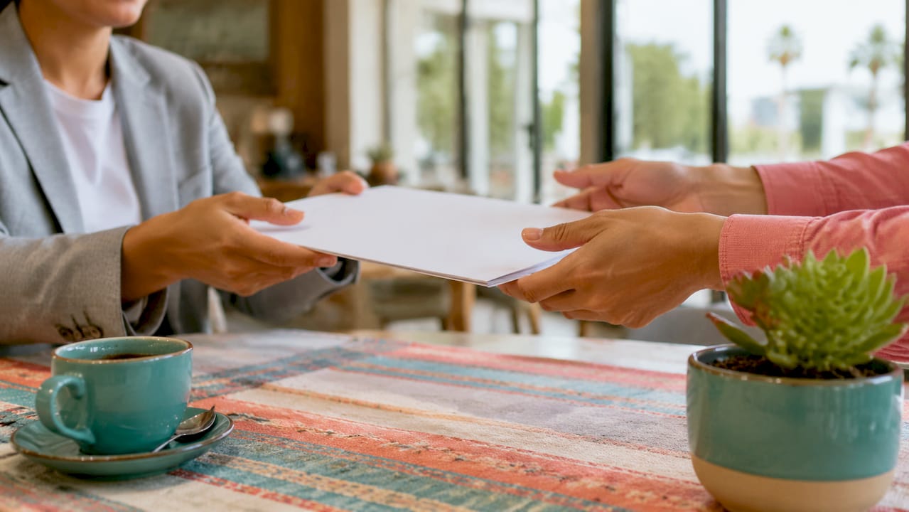 Hands exchanging property deed on desk