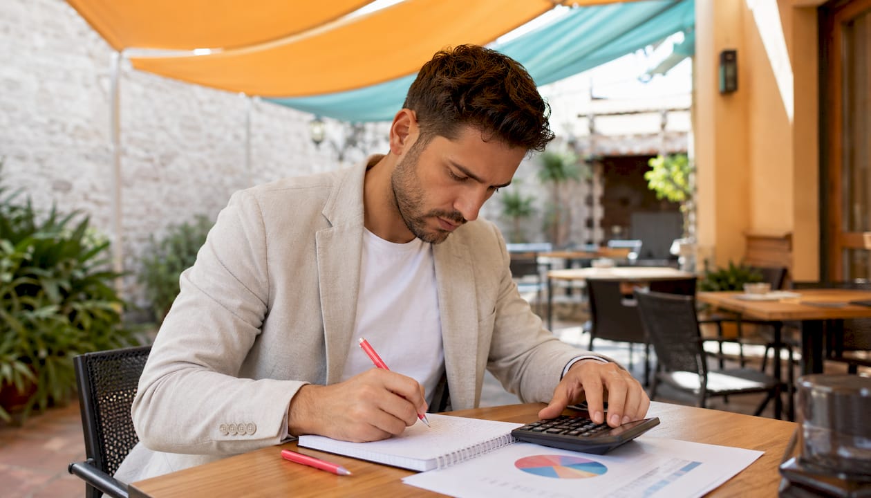 Personas revisando cálculos de porcentajes en el sector inmobiliario con una calculadora en mano