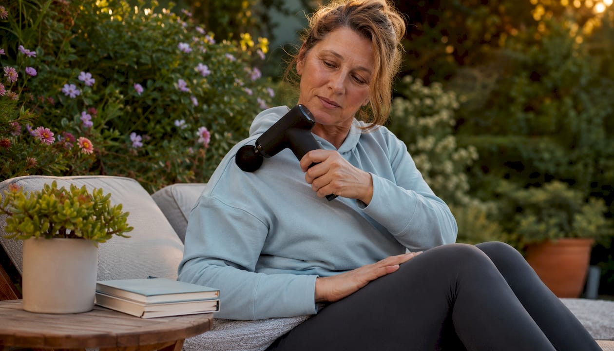 Woman using percussion massage device at home