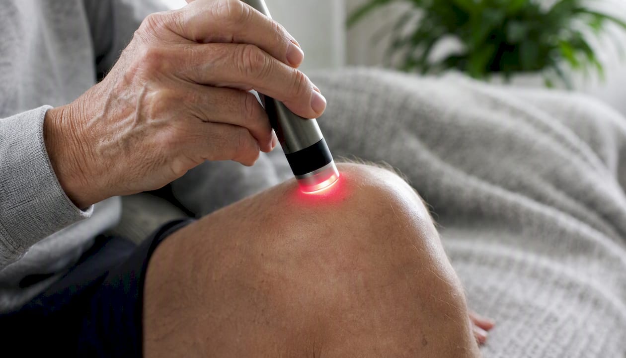 Hand applying red-light therapy to arthritic joint
