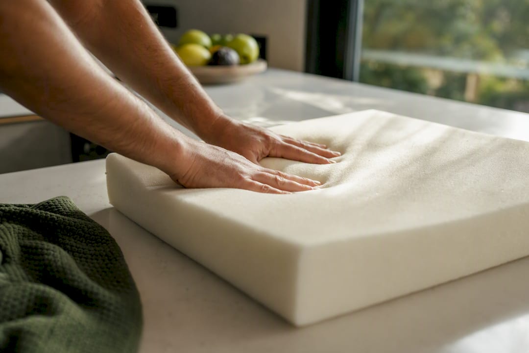 Hands pressing foam cushion to test firmness