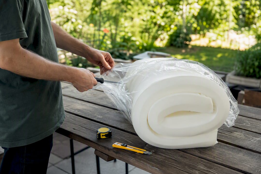 Hands cutting open vacuum-sealed foam cushion