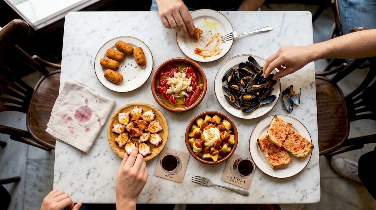 Imagen tomada desde arriba de una mesa repleta de tapas tradicionales, donde se aprecian todos sus detalles auténticos.