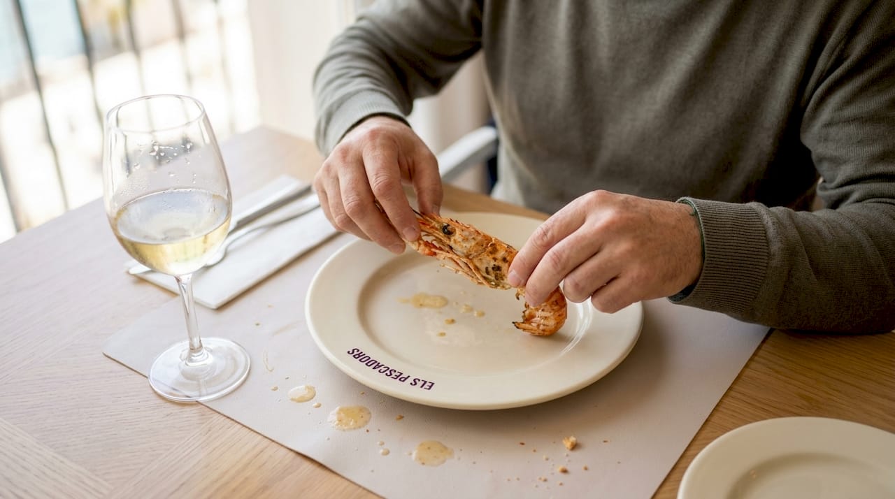 Disfrutando de un langostino acompañado de una copa de vino blanco.