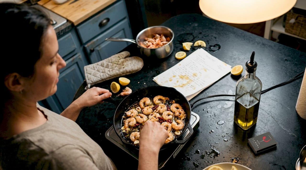 Un cocinero casero preparando unas gambas al ajillo en la sartén