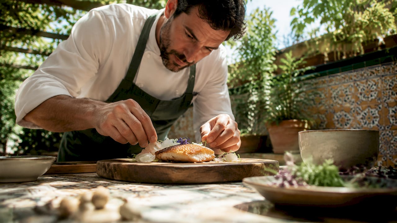 Chef plating crispy fish skin in kitchen