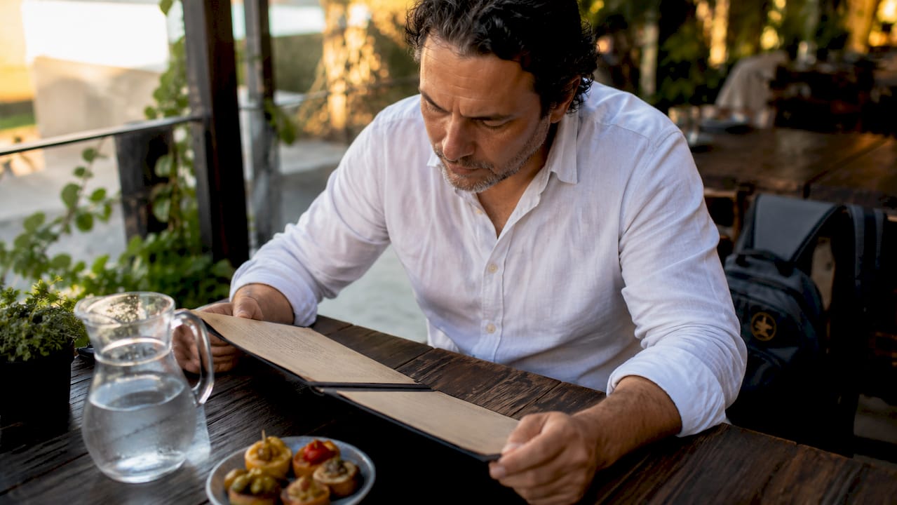 Hombre hojeando la carta y decidiendo qué pedir entre los platos clásicos