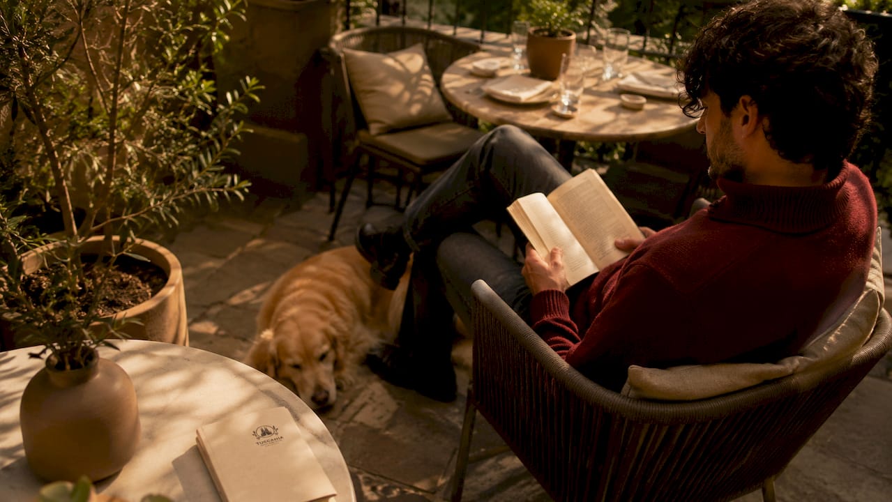 En la terraza, una mesa invita a sentarse mientras un perro tranquilo descansa a su lado.