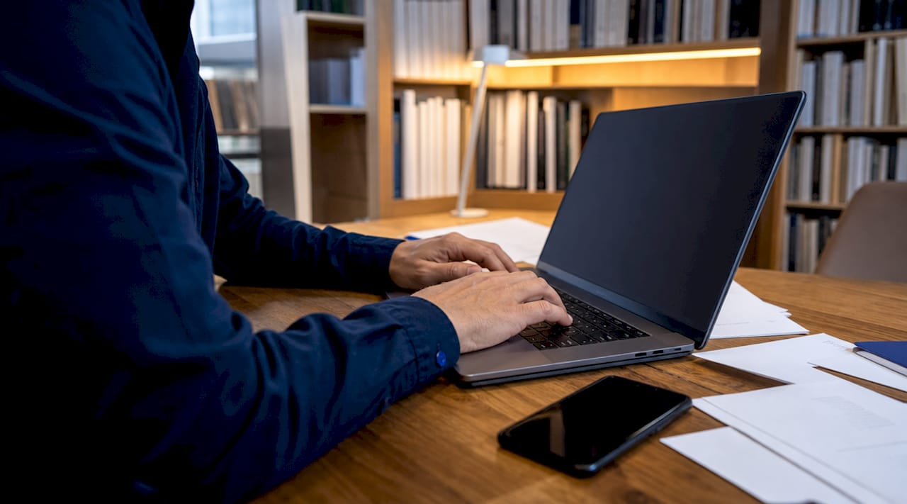 Des mains s’activent sur un clavier d’ordinateur au bureau.