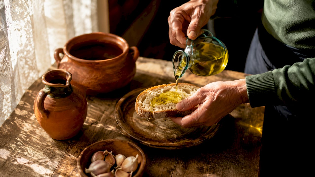 Hands preparing Pa amb tomàquet at a kitchen table