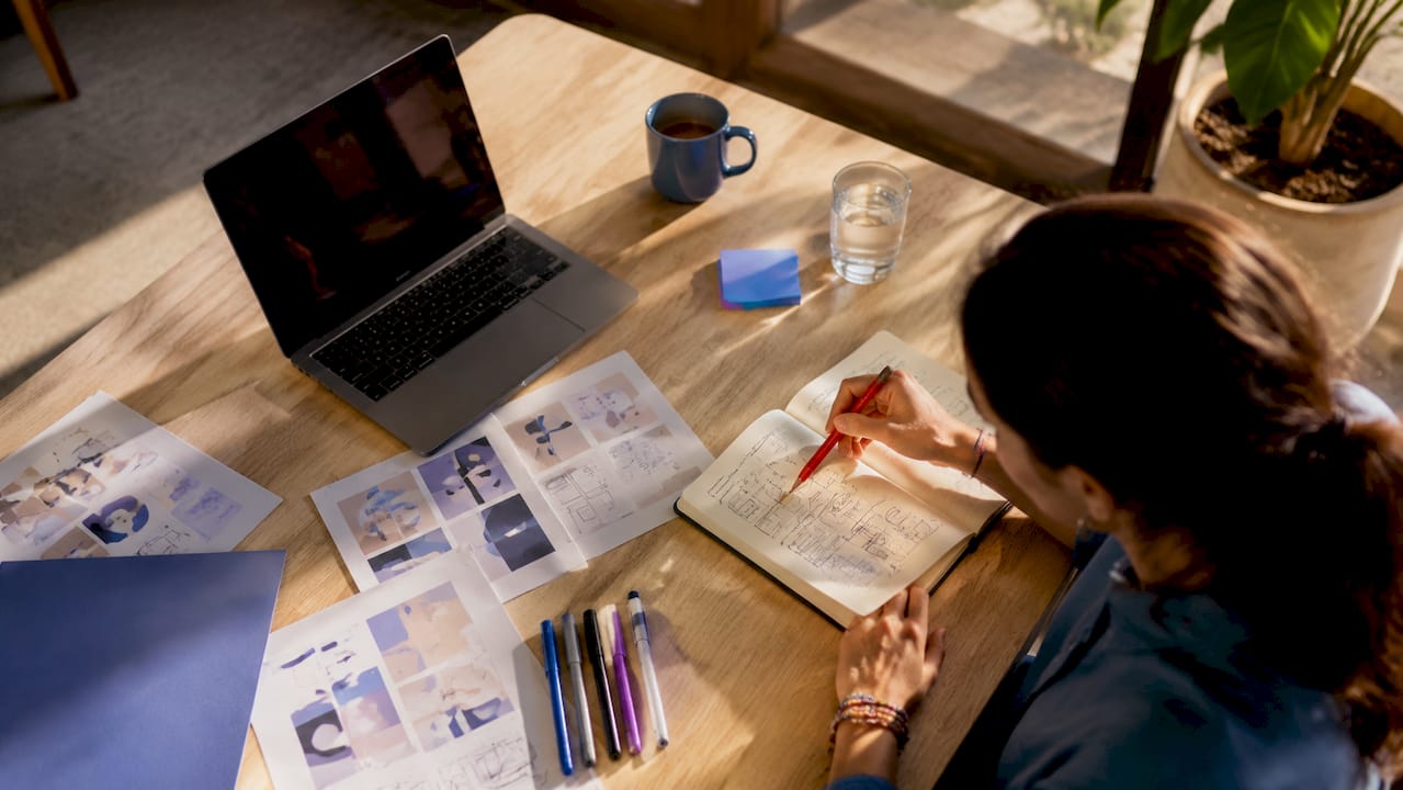 Une main en train de griffonner des idées de formats Instagram dans un carnet
