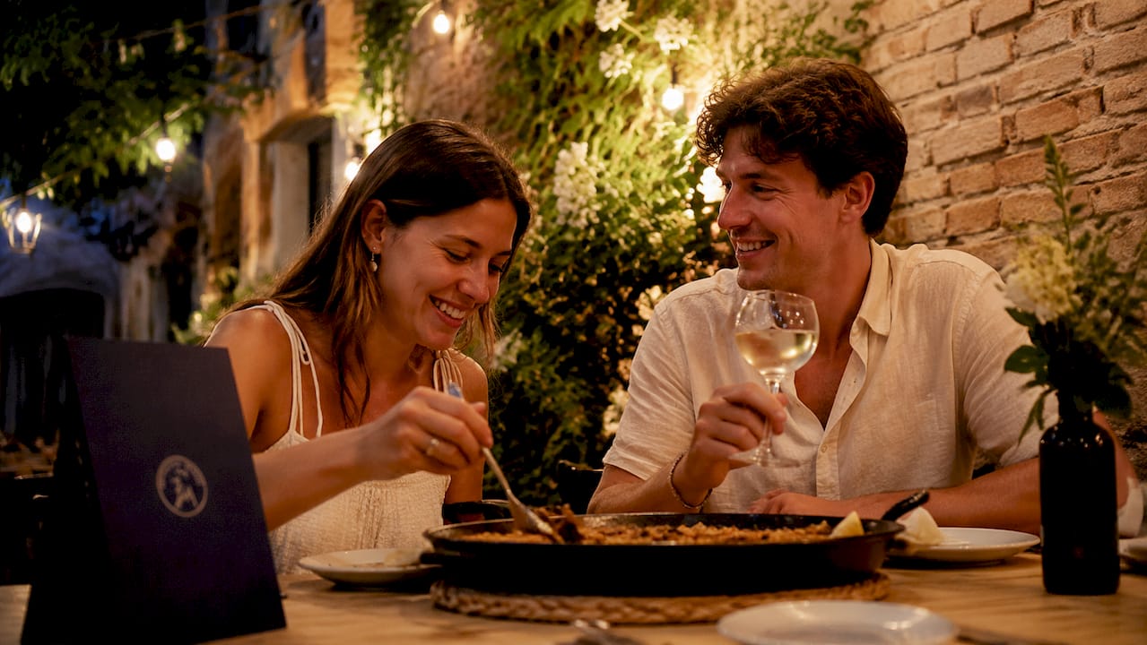 Una pareja de turistas disfruta de la auténtica gastronomía catalana en un restaurante local.