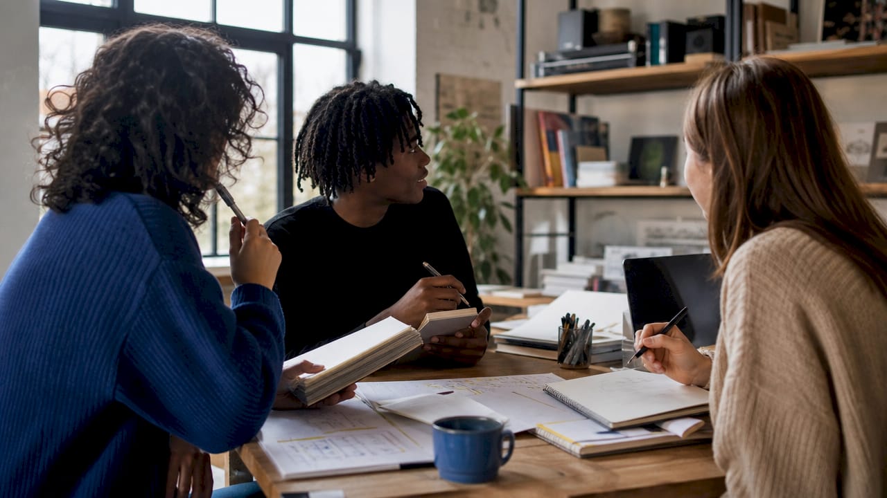 Un groupe de jeunes créateurs numériques échange sur leurs projets innovants autour d’un café en plein centre-ville.