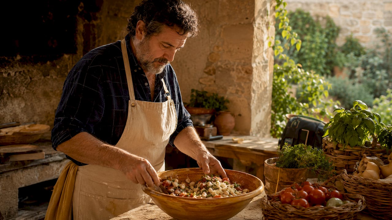El chef prepara el empedrat de mongetes mezclando cuidadosamente todos los ingredientes.