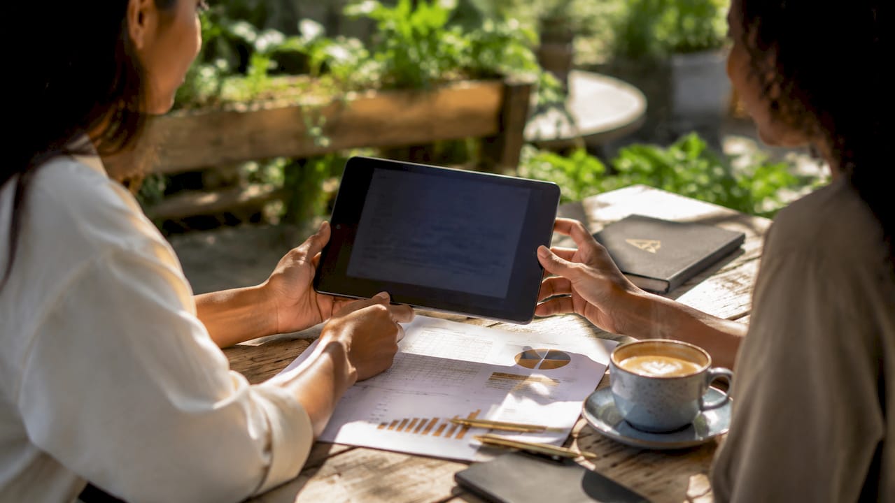 Manos con una tablet y apuntes de palabras clave sobre la mesa de una cafetería