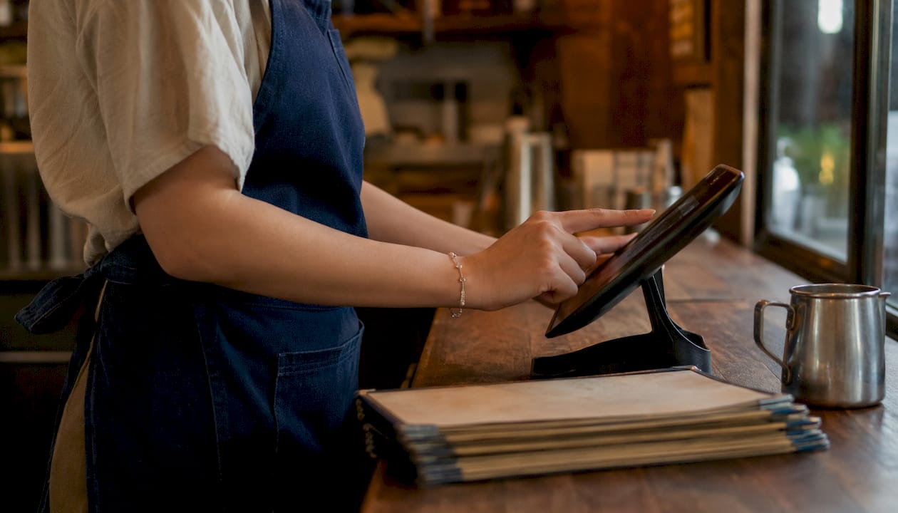 Hands using touchscreen POS system in restaurant office