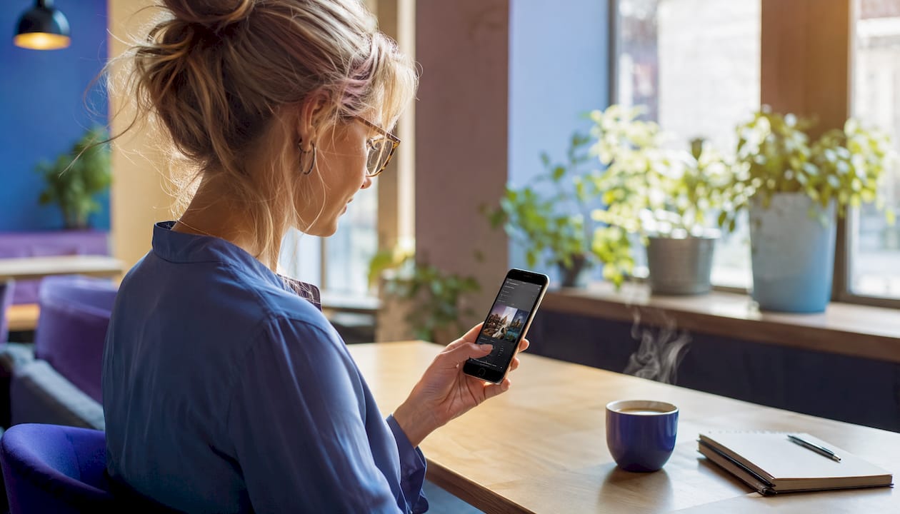 Une femme parcourt des Reels sur son smartphone du bout des doigts.