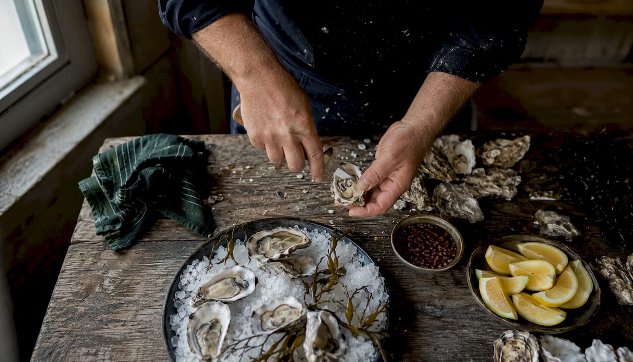 Chef hands shucking oysters on kitchen counter