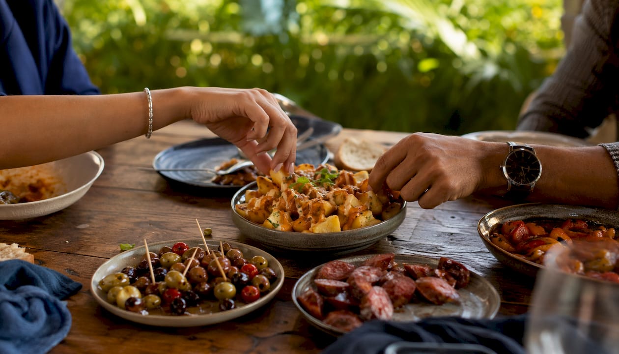 Overhead hands passing tapas plate at table